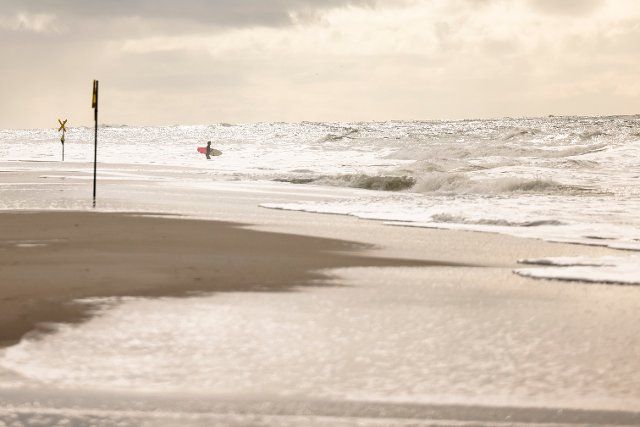 27 September 2022, Schleswig-Holstein, Westerland\/Sylt: A surfer stands on the Brandenburg beach. Photo: Frank Molter\/dpa