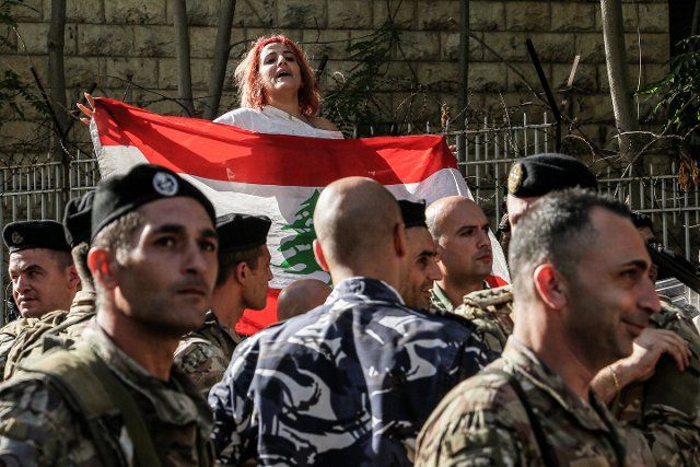 27 September 2022, Lebanon, Beirut: A demonstrator waves the Lebanese flag as she stands behind Lebanese army during a protest by families of the victims of 04 August 2020 Beirut port blast, outside Beirut judiciary palace, against the potential appointment of a second judge for the blast investigation The higher Judicial council met to discuss appointing a second judge to a stalled investigation into the explosion that left more than 200 people dead. Photo: Marwan Naamani\/dpa