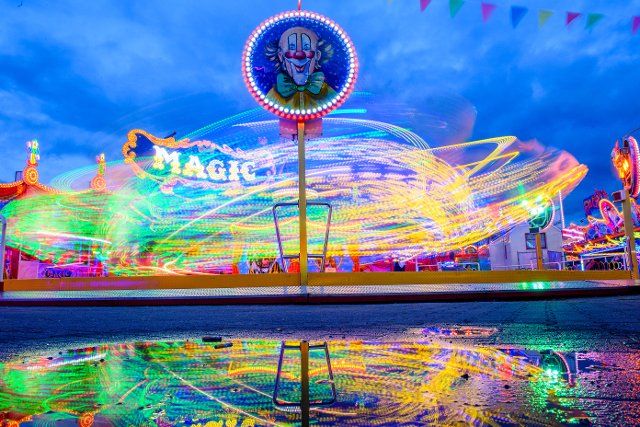 27 September 2022, Saxony-Anhalt, Magdeburg: A carousel turns in the evening at the autumn fair of the capital of Saxony-Anhalt, reflected in a puddle of rain. The fair had been opened on October 23, 2022 and lasts until October 16, 2023. According to the "Verein selbständiger Gewerbetreibender, Markt- und Messereisender gegründet 1885" (Association of independent tradesmen, market and fair travelers founded in 1885), it is the 1011st time that an autumn fair is held in Magdeburg after the first mention in 1010. In the pandemic year 2020 the autumn fair was cancelled. This makes the Magdeburg Autumn Fair the oldest folk festival in Germany, according to the association. Photo: Klaus-Dietmar Gabbert\/dpa
