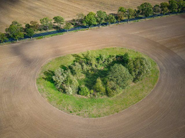 27 September 2022, Brandenburg, Müncheberg: On a harvested grain field there is a so-called "Soll", a small depression, usually with a water hole (aerial photo with a drone). Such "tarns" were often formed as a result of ice ages in northeastern Germany. Today, as biotopes, they form ecologically valuable islands in areas heavily used for agriculture. Photo: Patrick Pleul\/dpa\/ZB