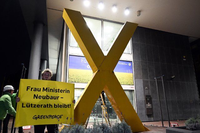 28 September 2022, North Rhine-Westphalia, Duesseldorf: Greenpeace activists set up a yellow X in front of the North Rhine-Westphalian Ministry of Economics. One activist holds a poster "Ms. Minister Neubaur - Lützerath stays!". With an action in front of the Ministry of Economics, the environmental organization Greenpeace has called for the preservation of the abandoned lignite village of Lützerath on the edge of the Garzweiler open pit mine. Photo: Federico Gambarini\/dpa