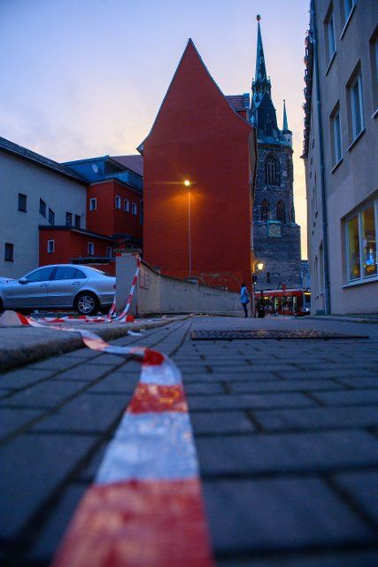 28 September 2022, Saxony-Anhalt, Halle (Saale): Barrier tape lies on the ground in an alley behind the Marktschlösschen. Two girls and a woman were seriously injured in an explosion in a public toilet of the building the night before. Residents around the explosion site were evacuated. Photo: Klaus-Dietmar Gabbert\/dpa