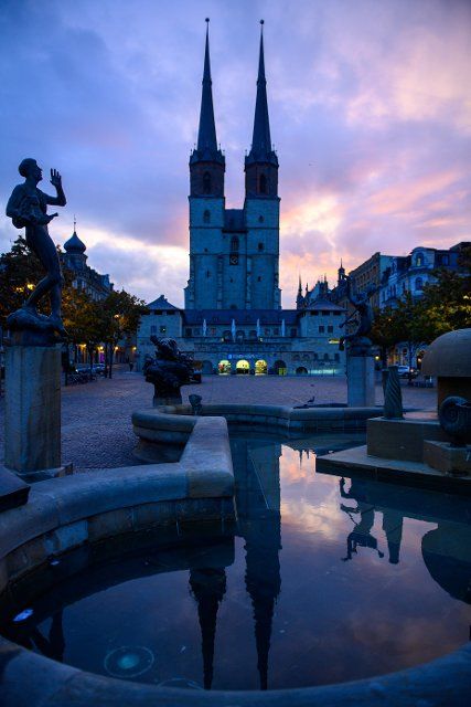 28 September 2022, Saxony-Anhalt, Halle (Saale): The morning dawns over the market church in Halle an der Saale, its spires reflected in a fountain. The region is in for a gloomy autumn day with prolonged rain. Photo: Klaus-Dietmar Gabbert\/dpa\/ZB