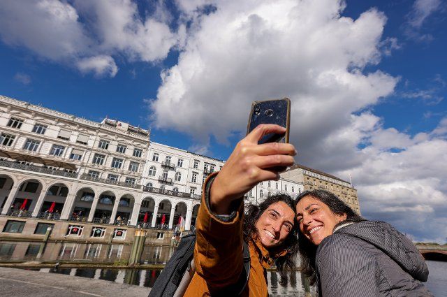 30 September 2022, Hamburg: Greek tourists take advantage of the mild, sunny autumn weather to take a souvenir photo in front of the Alsterarkaden in Hamburg. Photo: Ulrich Perrey\/dpa