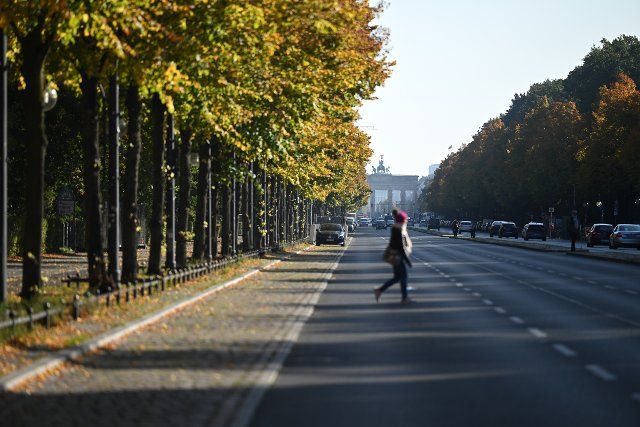 30 September 2022, Berlin: A young woman crosses the Straße des 17. Juni in the sunshine. Photo: Britta Pedersen\/dpa