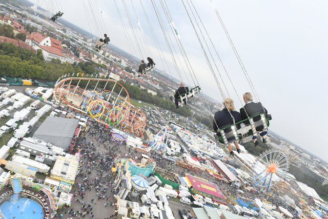 25 September 2022, Bavaria, Munich: From a giant chain carousel, the Ferris wheel and the five-loop roller coaster can be seen under overcast skies and light rain. The Wiesn will be held from September 17 to October 3, 2022. Photo: Felix Hörhager\/dpa