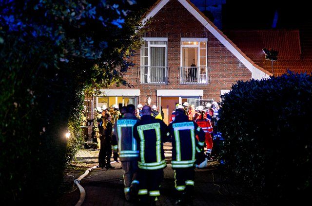 25 September 2022, Lower Saxony, Wardenburg: Numerous firefighters and rescue workers stand in front of an old people\