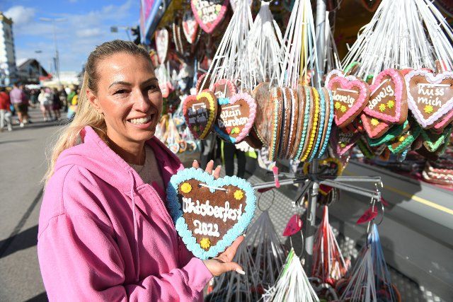 26 September 2022, Bavaria, Munich: Michaela Schifferl, the owner of the Wiesn booth "Herzmalerei" holds a heart with the inscription "Oktoberfest 2022" in her hand. The Wiesn will take place from September 17 to October 3, 2022. Photo: Felix Hörhager\/dpa