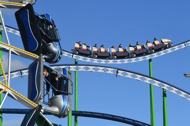26 September 2022, Bavaria, Munich: Cars of a roller coaster ride against a blue sky at the Oktoberfest. The Wiesn will be held from September 17 to October 3, 2022. Photo: Felix Hörhager\/dpa