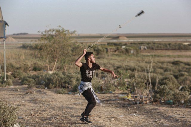 26 September 2022, Palestinian Territories, Gaza: A Palestinian man hurls stones during a demonstration near the border fence with Israel, east of Gaza City. Palestinian Hamas Islamist movement threatened "repercussions" over the Jewish visits to Jerusalem\