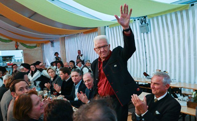 26 September 2022, Baden-Wuerttemberg, Stuttgart: Winfried Kretschmann (Bündnis 90\/Die Grünen), Minister President of Baden-Württemberg, waves to the audience during the welcoming ceremony in the marquee at the Historisches Volksfest on Schlossplatz. Thomas Strobl (CDU), Minister of the Interior of Baden-Württemberg, is seated on the right. Members of the state government and the government factions met for an evening at the folk festival. Photo: Bernd Weißbrod\/dpa