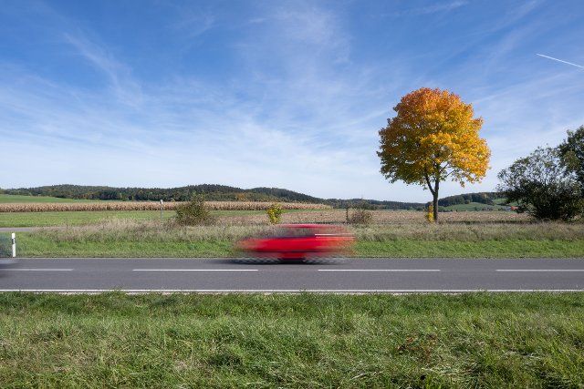 05 October 2022, Baden-Württemberg, Gamertingen: A car drives past an autumn tree on a country road. Photo: Marijan Murat\/dpa