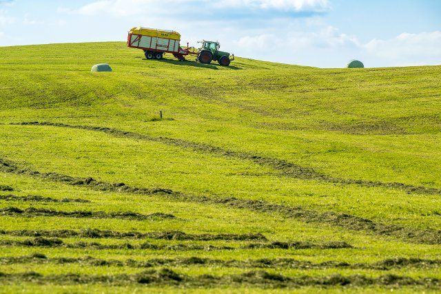 06 October 2022, Bavaria, Aschau: A farmer collects the fresh grass on his hilly land with his machine. Photo: Peter Kneffel\/dpa