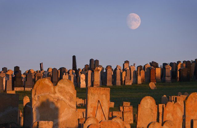 06 October 2022, Bavaria, Rödelsee: The waxing moon rises over the old Jewish cemetery lying in the evening light. Photo: Karl-Josef Hildenbrand\/dpa