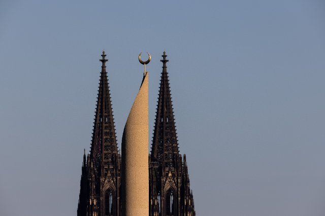 06 October 2022, North Rhine-Westphalia, Cologne: In the light of the setting sun, a minaret of the central mosque of the DITIB (Turkish-Islamic Union of the Institute for Religion) and the Cologne Cathedral can be seen. At Cologne\