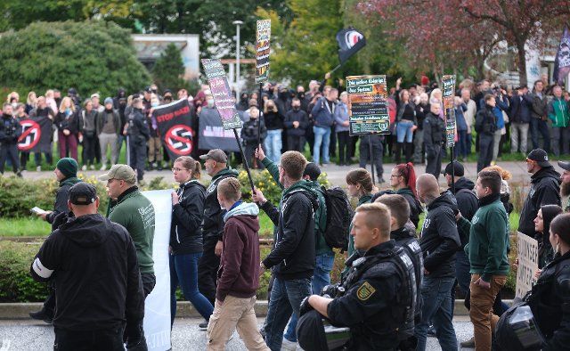 02 October 2022, Saxony, Plauen: Participants of a right-wing demonstration (in front) walk along a street, while in the background left-wing activists protest against the march. About two hundred people took part in the march of the right-wing extremist minor party "Der dritte Weg". Photo: Sebastian Willnow\/dpa
