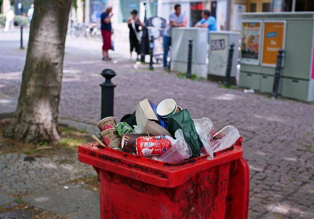 26 June 2022, Berlin: 26.06.2022, Berlin. A full trash can is overflowing on a public square in front of the Steglitz town hall in Steglitz. Much of the trash consists of disposable coffee cups. Photo: Wolfram Steinberg\/dpa Photo: Wolfram Steinberg\/dpa