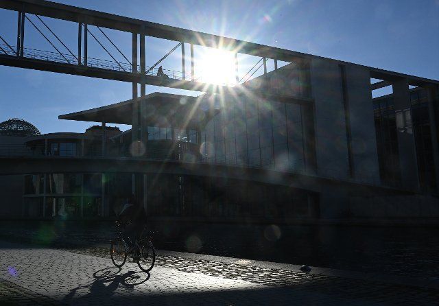 26 October 2022, Berlin: A cyclist rides along the banks of the Spree River in the government district. Photo: Britta Pedersen\/dpa\/ZB