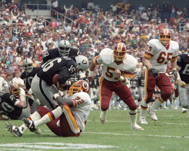 Washington Redskins right defensive end Dexter Manley (72) sacks Los Angeles Raiders quarterback Jim Plunkett (16) during their game at RFK Stadium in Washington, D.C. on October 2, 1983. Trailing Manley on the play are right linebacker Rich Milot (57) and left defensive tackle Dave Butz (65). Credit: Howard L. Sachs \/ CNP