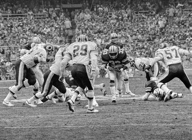 Dallas Cowboys running back running back Tony Dorsett (33) carries the ball in the NFC Championship Game at RFK Stadium in Washington, DC on Saturday, January 22, 1983. Defending for the Redskins are left defensive tackle Dave Butz (65), free safety Mark Murphy (29), right defensive end Dexter Manley (72), and right linebacker Rich Milot (57). The Redskins won the game and a trip to Super Bowl XVII, 31 - 17. Credit: Ron Sachs \/ CNP