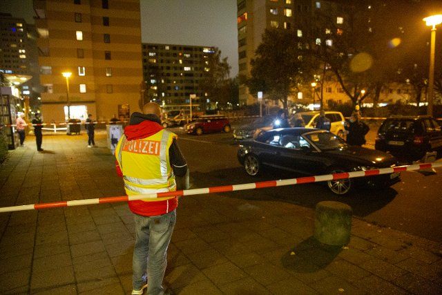 16 November 2022, Berlin: A police officer stands in front of a car on Dolgenseestraße in Friedrichsfelde. A driver has been seriously injured by gunshots in Berlin-Lichtenberg. The perpetrator shot from the sidewalk several times at the car of the 55-year-old driver, according to police. The shooter fled. A homicide squad is investigating. Photo: Paul Zinken\/dpa