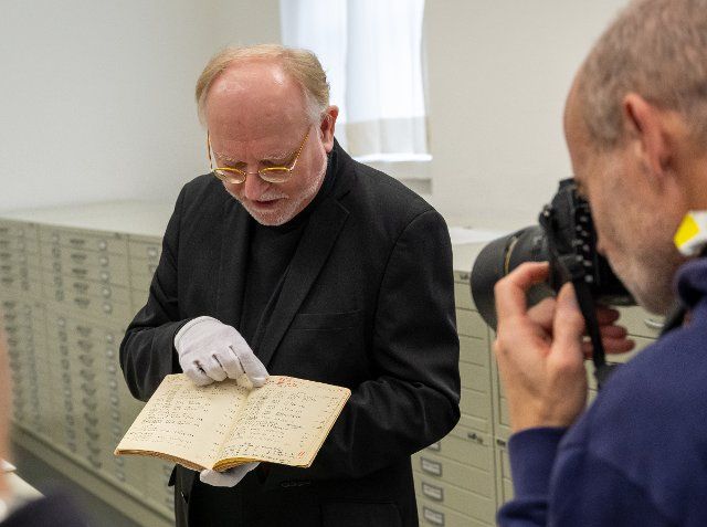 22 November 2022, Bavaria, Munich: Wilhelm Füßl, long-time head of the archive of the Deutsches Museum, shows a photographer the original laboratory book of the chemist and Nobel Prize winner Otto Hahn during a press tour of the archive of the Deutsches Museum. Photo: Peter Kneffel\/dpa