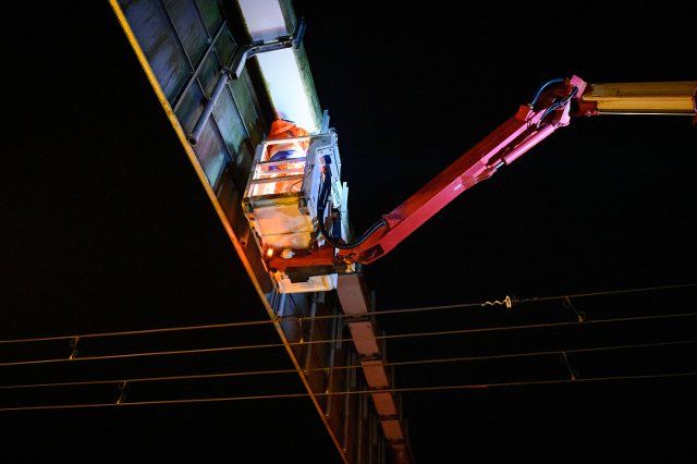 30 November 2022, Schleswig-Holstein, Hamberge: Two workers in a cherry picker cage install the suspension for a measuring device on a gantry above the power lines. On Wednesday evening, installation work started on the E-Highway Schleswig-Holstein on Highway 1 as part of the research program. Photo: Jonas Walzberg\/dpa