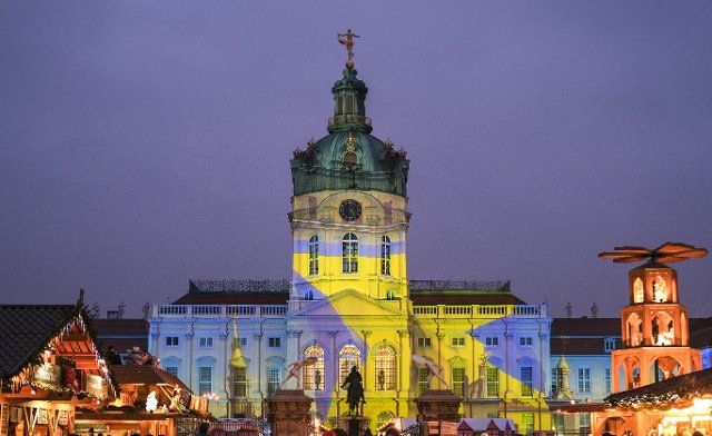 01 December 2022, Berlin: The facade of Charlottenburg Palace is also illuminated with the colors of the Ukrainian flag in blue and yellow during the currently open Christmas market. Through a partnership with Kiev, among other things, donations are collected. The association Ukraine-Hilfe Berlin and the Ukrainian Orthodox church community in Berlin will be provided with three of the total of 20 tent pagodas. Photo: Jens Kalaene\/dpa