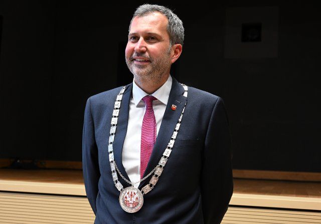 30 November 2022, Brandenburg, Cottbus: The new mayor of Cottbus, Tobias Schick (SPD), smiles with the chain of office after his inauguration in the town hall. Schick had prevailed in a runoff election on 09 October with 68.6 percent against AfD candidate L. Schieske. Photo: Michael Helbig\/dpa-Zentralbild\/dpa