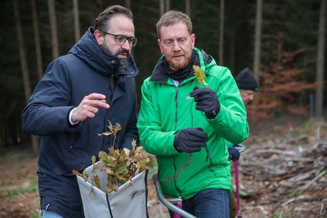 30 November 2022, Saxony, Mulda: Sebastian Gemkow (l, CDU), Minister of Science of Saxony, Michael Kretschmer (CDU), Minister President of Saxony, plant one of the first 300 oaks on the prominent Karlshügel hill, which is currently bare due to the bark beetle. To compensate for the dramatic damage to Saxony\