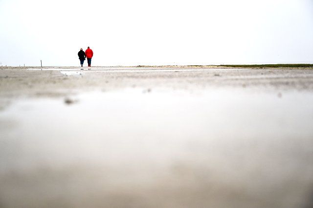 30 November 2022, Lower Saxony, Varel: Walkers go through the mudflats in front of the beach of Dangast. The 14th trilateral Wadden Sea Conference of Germany, Denmark and the Netherlands will end in Wilhelmshaven on December 1, 2022. The conference discussed the protection of the Unesco World Heritage Site Wadden Sea. Photo: Sina Schuldt\/dpa