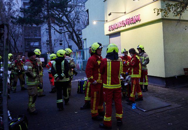 04 December 2022, Berlin: Firefighters stand in front of a retirement home in Berlin-Neukölln. One person has died in a fire at a home for the elderly in Berlin-Neukölln. Four people were injured but rescued, said a fire department spokesman at the scene. Photo: Annette Riedl\/dpa