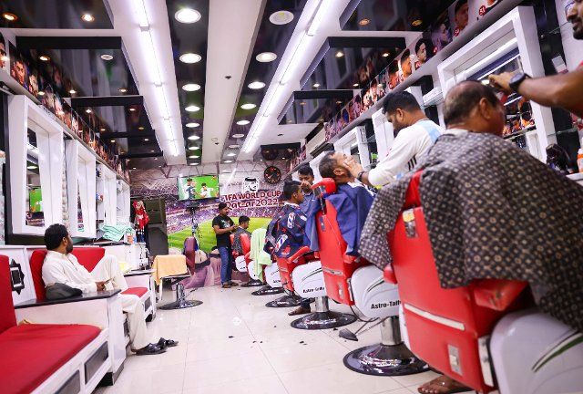 03 December 2022, Qatar, Doha: In a barbershop in the shopping center next to the "Asian Town Cricket Stadium," the Netherlands-USA match is playing on a TV on the wall. In the cricket stadium, officially called the "Fan Zone Industrial Area," thousands of foreign workers watch the World Cup matches on a big screen every evening. Photo: Christian Charisius\/dpa