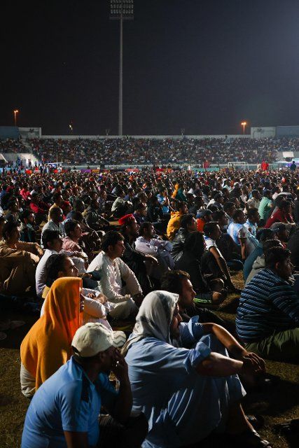 PRODUCTION - 03 December 2022, Qatar, Doha: Workers, mainly from India, Bangladesh, Nepal and other poorer Asian countries, watch the Argentina-Australia match on a big screen at the Asian Town Cricket Stadium. In the cricket stadium, officially called the "Fan Zone Industrial Area," thousands of foreign workers watch the World Cup matches every evening. Photo: Christian Charisius\/dpa