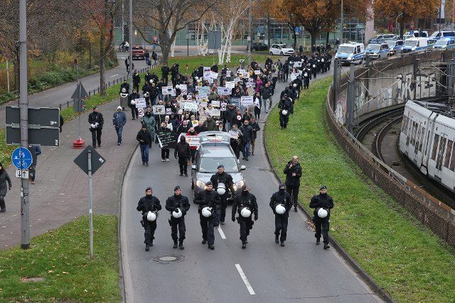 04 December 2022, North Rhine-Westphalia, Cologne: Pro-Russian demonstrators, who oppose arms deliveries to Ukraine, march through the city accompanied by police officers. Photo: David Young\/dpa