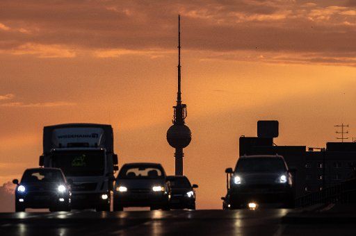 12 July 2018, Germany, Berlin: Vehicles driving on the Lichtenberg bridge in the evening. The TV tower is silhouetted in the light of the setting sun in the background. Photo: Paul Zinken\/
