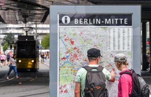10 July 2018, Germany, Berlin: Tourists find their way around with the help of a public city map at Alexanderplatz. Photo: Jens Kalaene\/dpa-Zentralbild\/