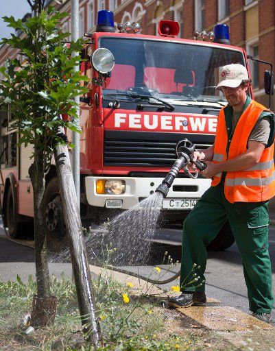 25 July 2018, Chemnitz, Germany: Sebastian Müller from the Parks and green areas Department of the city of Chemnitz irrigates street trees in the city with support from the fire brigade. Especially young trees and new plantations are supplied with water due to the current drought. Photo: Hendrik Schmidt\/dpa-Zentralbild\/