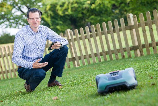 29 August 2018, Stuttgart, Germany: Henning von Boxberg, President of the Bosch Power Tools Division, sits next to an Indego lawn mower robot. Photo: Sebastian Gollnow\/