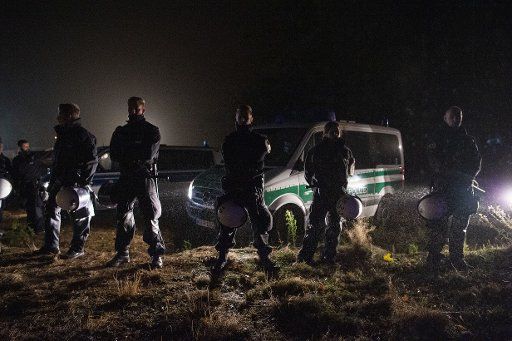 24 October 2018, North Rhine-Westphalia, Kerpen-Manheim: During the evacuation of the activist camp of the action alliance "Ende Gelände", police officers are standing in the headlights of their cars in the rain. The police started late Wednesday evening 24.10.2018 to clear a protest camp of opponents of lignite near the Hambach forest. About one third of the approximately 100 activists there had voluntarily left the camp in Kerpen-Manheim before, said a spokeswoman for the Aachen police. The others would be carried away. There would be no greater resistance to evacuation. Photo: Christophe Gateau\/