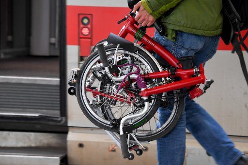 15 November 2018, Bavaria, München: A passenger carries the folding bike classic Brompton on the platform at Munich Central Station. Photo: Tobias Hase\/