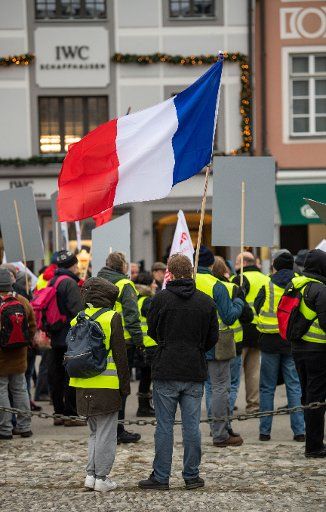 15 December 2018, Bavaria, München: Demonstrators in yellow warning vests and with a French flag stand at a rally in downtown Munich. The demonstrators called for solidarity with the French yellow vests. Photo: Lino Mirgeler\/