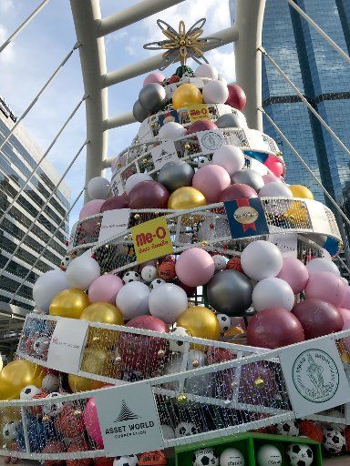 04 December 2018, Thailand, Bangkok: In front of a shopping centre stands a stylized Christmas tree, decorated not only with balls, but also with footballs and basketballs. (to dpa "From the Cucumber to the Basketball - Who hangs what on the Christmas Tree" from 19.12.2018) Photo: Christoph Sator\/