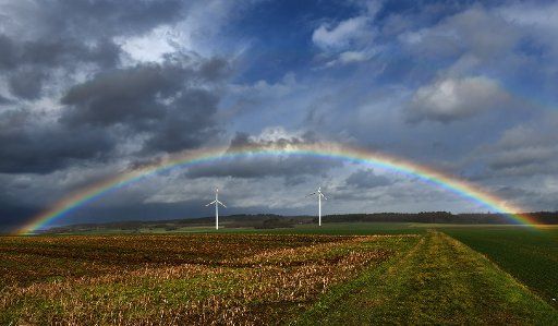 04 March 2019, Hessen, Reuters: A rainbow spans a stormy sky in the Vogelsberg near Reuters. Below are two windmills. Photo: Uwe Zucchi\/