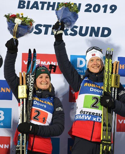 14 March 2019, Sweden, Stersund: Biathlon: World Championship, Individual Relay, Mixed. Johannes Thingnes Bö and Marte Olsbu Roeiseland from Norway celebrate their victory on the podium at the Flower Ceremony. Photo: Sven Hoppe\/