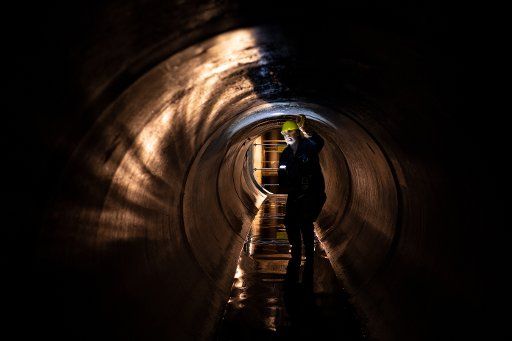 28 March 2019, Berlin: During a press event of Berliner Wasserbetriebe in Berlin-Friedenau, a worker looks at part of a new, approximately two-kilometer-long water channel underground. This sewer can take up and safely discharge about 3500 cubic meters of wastewater and is part of a new construction and renewal program of the water utilities with investments of about 21 million euros. Photo: Ralf Hirschberger\/