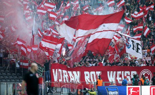 06 April 2019, Berlin: Soccer: Bundesliga, Hertha BSC - Fortuna Düsseldorf, 28th matchday in the Olympic Stadium. Düsseldorf fans ignite pyrotechnics and wave flags. Photo: Andreas Gora\/dpa - IMPORTANT NOTE: In accordance with the requirements of the DFL Deutsche Fußball Liga or the DFB Deutscher Fußball-Bund, it is prohibited to use or have used photographs taken in the stadium and\/or the match in the form of sequence images and\/or video-like photo sequences.
