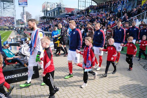 06 April 2019, Schleswig-Holstein, Kiel: Soccer: 2nd Bundesliga, Holstein Kiel - FC St. Pauli, 28th matchday. The Kiel players Kenneth Kronholm (l-r), Alexander Mühling, Jannik Dehm, Jonas Meffert, Stefan Thesker and Masaya Okugawa will be playing on the court with their running-in children. Photo: Frank Molter\/dpa - IMPORTANT NOTE: In accordance with the requirements of the DFL Deutsche Fußball Liga or the DFB Deutscher Fußball-Bund, it is prohibited to use or have used photographs taken in the stadium and\/or the match in the form of sequence images and\/or video-like photo sequences.