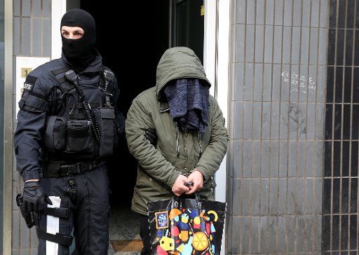 09 April 2019, North Rhine-Westphalia, Köln: A federal policeman leads an arrested man from a residential building. The federal police have raided suspected smugglers. More than 300 investigators were deployed. They searched 30 objects. Photo: Oliver Berg\/