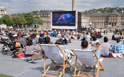 02 May 2019, Baden-Wuerttemberg, Stuttgart: Visitors to the International Festival of Animated Film sit on the Schlossplatz in front of a video screen. Photo: Bernd Weißbrod\/